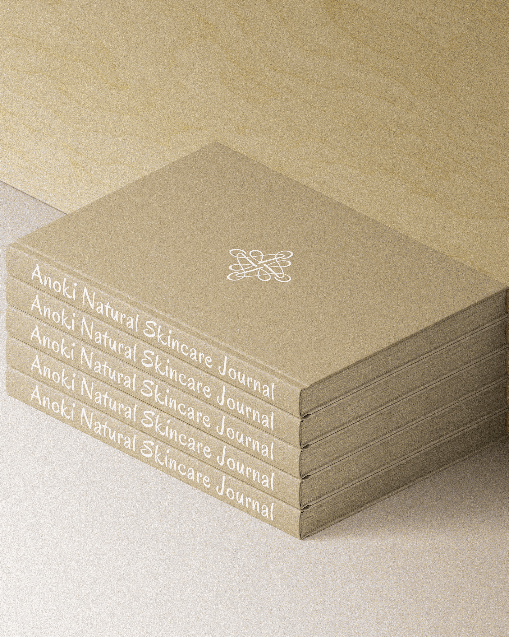 Stack of Anoki Natural Skincare Journals on a light wood surface.