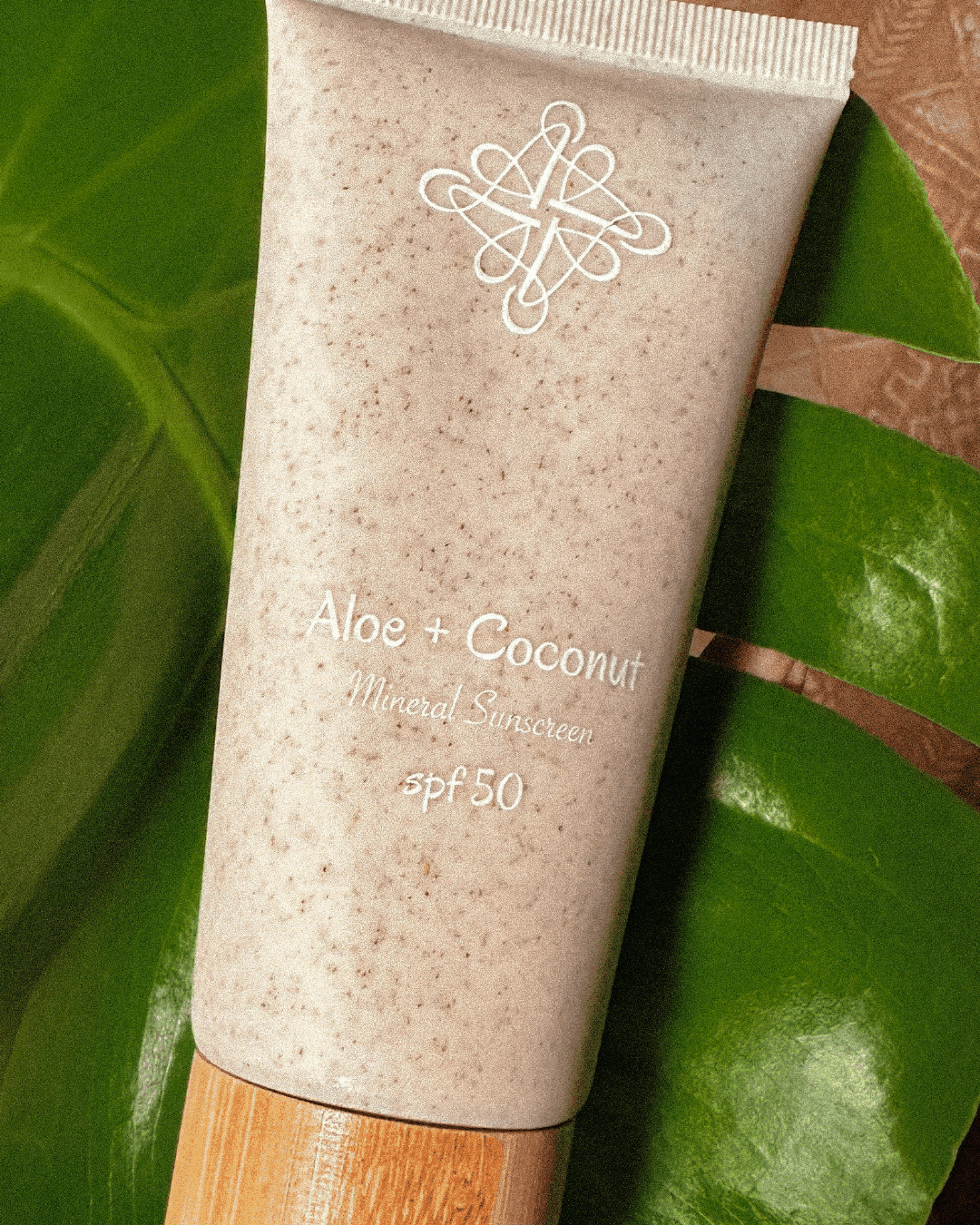 Aloe vera sunscreen with coconut, SPF 50, mineral-based, eco-friendly, on green leaf background.