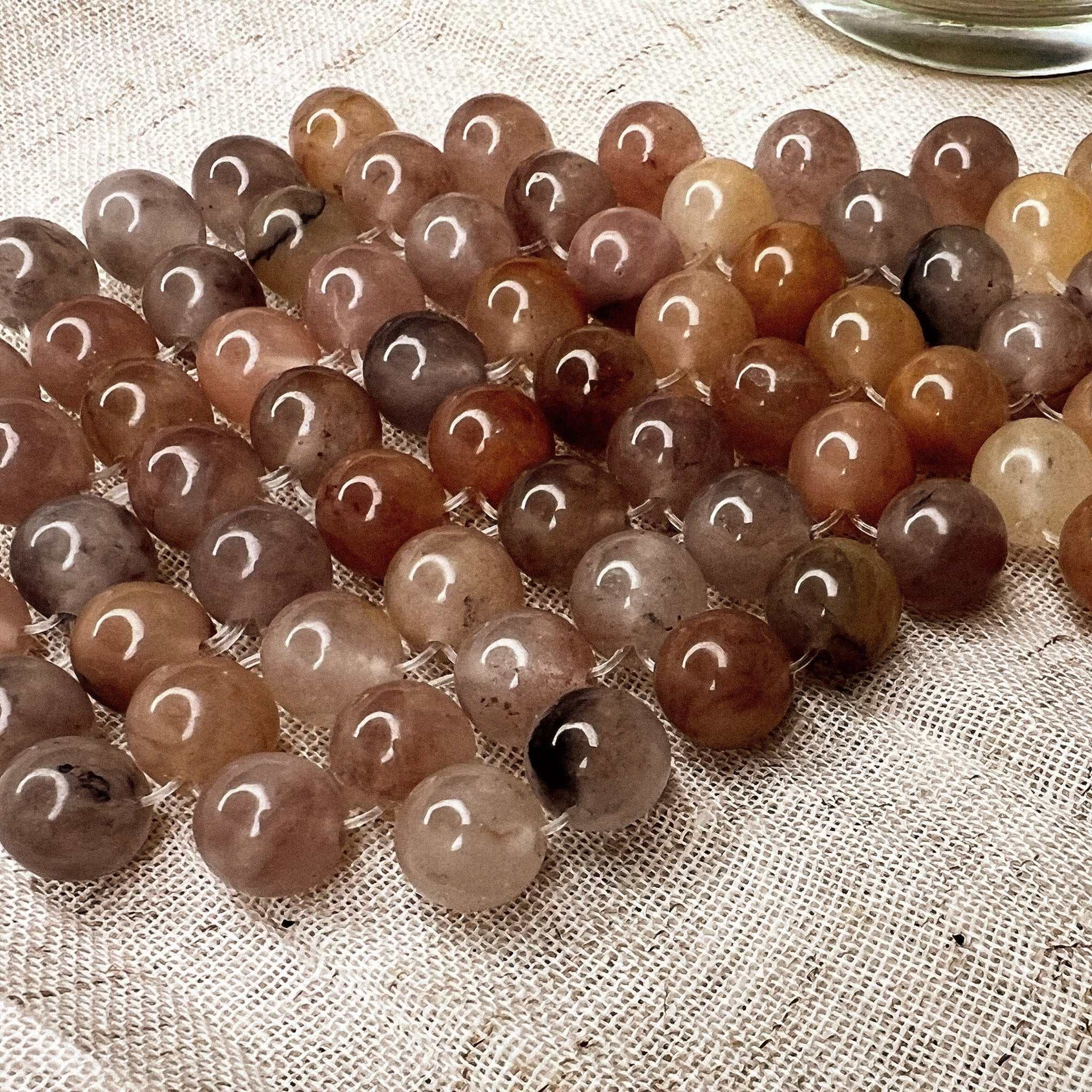 Natural jade stone eye mask made of smooth multi-jade stones on textured fabric background.