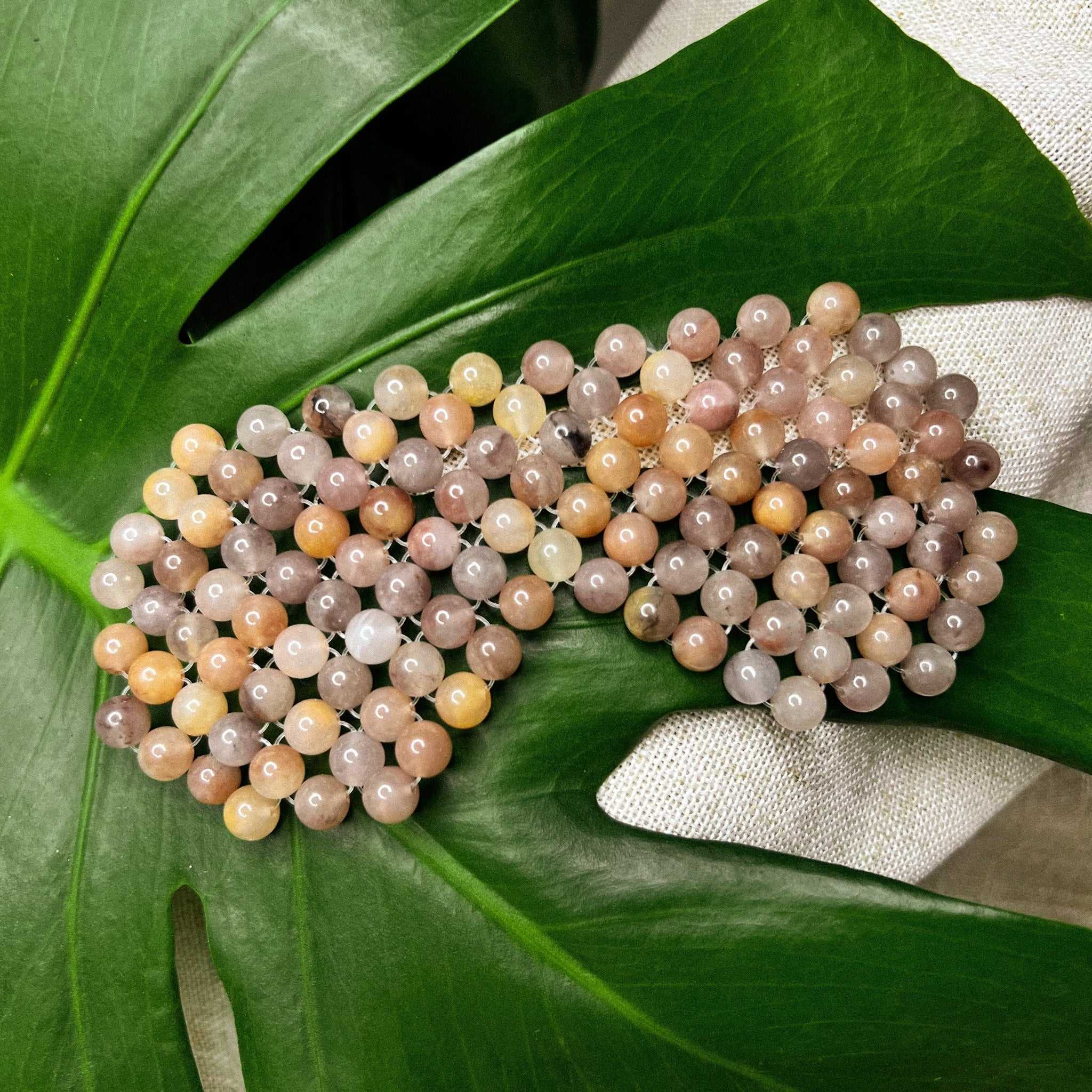 Natural jade stone eye mask on a green leaf surface.